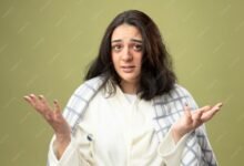 clueless young caucasian ill girl wearing robe wrapped plaid looking camera showing empty hands with thermometer underarm isolated olive green background 141793 75151