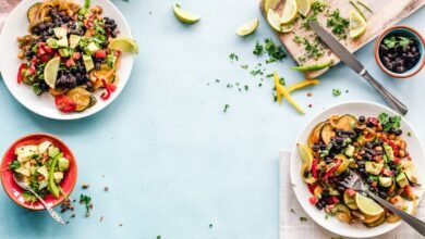 Colorful Mexican salad with avocado, black beans, and lime on a light blue surface.