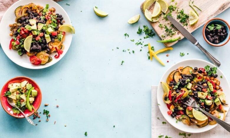 Colorful Mexican salad with avocado, black beans, and lime on a light blue surface.