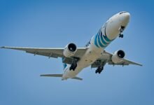 EgyptAir Boeing 777 flying against the clear blue sky over New York City.