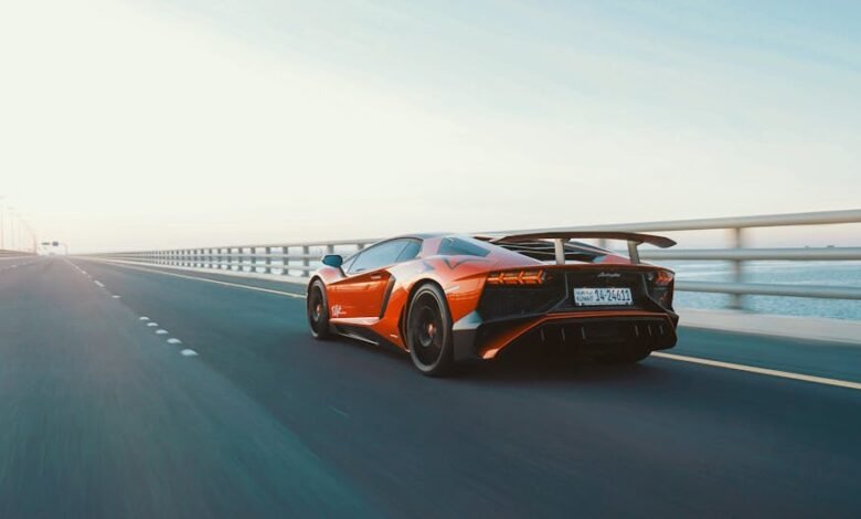 Dynamic shot of a red sports car speeding on an open coastal highway during the day.