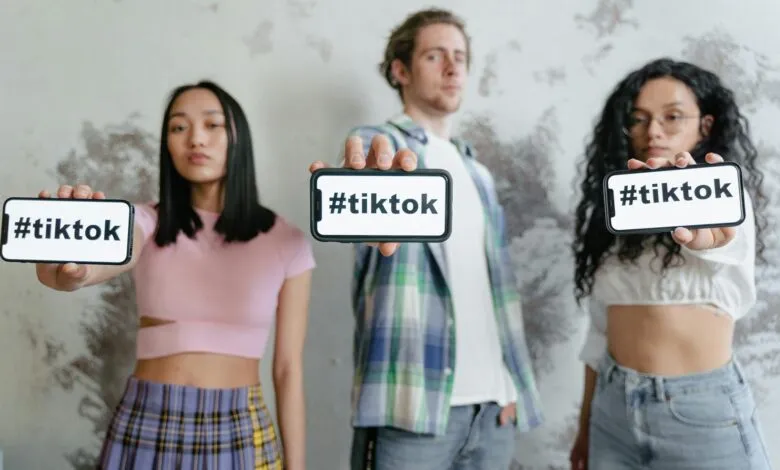 Group of young adults holding phones with #tiktok indoors, showcasing social media culture.