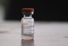 Close-up of a COVID-19 vaccine vial on a blurred background, highlighting medical treatment.