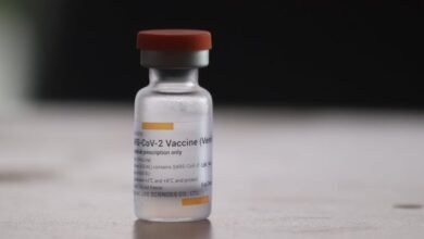 Close-up of a COVID-19 vaccine vial on a blurred background, highlighting medical treatment.