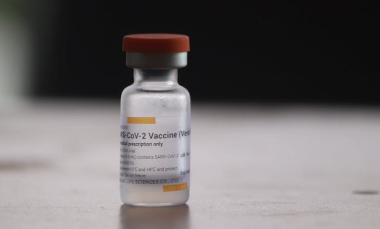 Close-up of a COVID-19 vaccine vial on a blurred background, highlighting medical treatment.